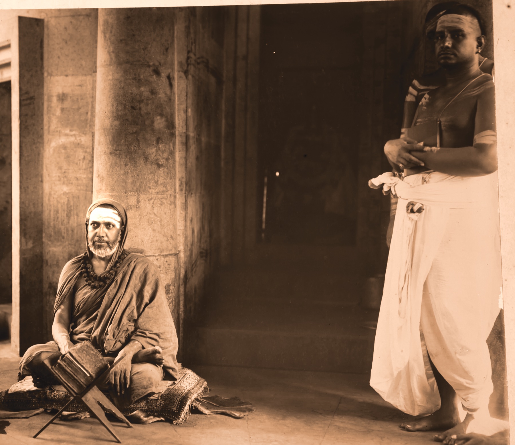 The Jagadguru seated with a volume open on a stand; T. K. Balasubrahmanyam standing beside him with a volume in his hands